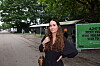 Kvinde står på sti ved Roskilde Festival med træer og grøn plakat i baggrunden.