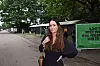 Kvinde står på sti ved Roskilde Festival med træer og grøn plakat i baggrunden.