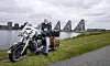 Verner Buhl sidder på en stor motorcykel ved vandet med karakteristiske bølgebygninger bagved.