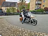 To personer på en stor cruiser-motorcykel i en gård mellem boligblokke