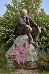 Lasse Korsgaard sidder på en malet sten med øko-gris i blomstrende have