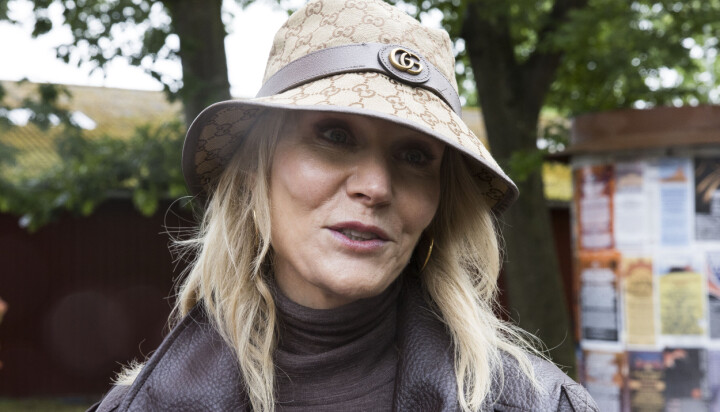 Kvinde med Gucci-hat og læderjakke interviewes udendørs på festivalplads.