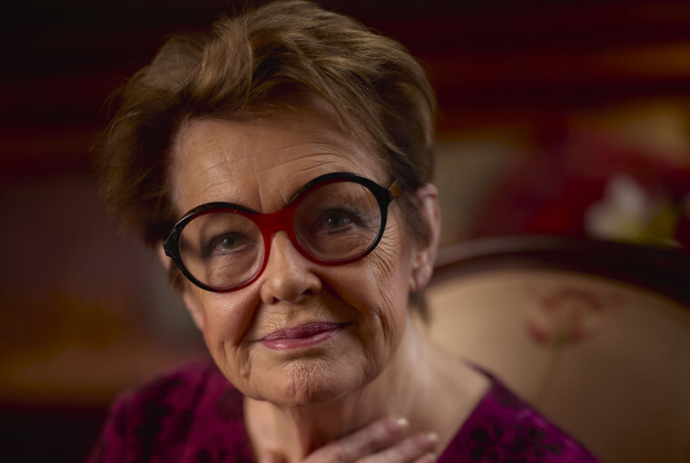 Skuespillerinden Ghita Nørby sidder indendørs med hånden mod brystet og ser mod kameraet.
