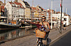 Kvinde på cykel med blomsterkurv kører langs Nyhavns kanal i aftensol