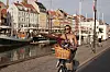 Kvinde på cykel med blomsterkurv kører langs Nyhavns kanal i aftensol