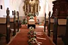 Kiste med blomsterkranse foran alter i lys kirke