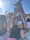 Smilende festivalgæst holder plastkrus med øl foran stor Tuborg-scene i solskin.