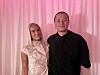 To personer poserer sammen foran lyserøde gardiner
