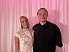 To personer poserer sammen foran lyserøde gardiner