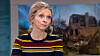 Kvinde i tv-studie foran billede af ødelagt bygning på skærmen bag hende.
