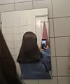 Person tager billede af sit hår i et badeværelsesspejl med mobiltelefon.