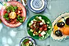 Farverigt sommerbord med salater, frugt og olivenolie hos Louisa Lorang