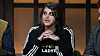 Person i sort Adidas-jakke sidder ved bord under paneldebat