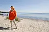Jeanne Boel står på en lys sandstrand ved Sønderborg med havet i baggrunden.