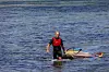 Anders Brandt trækker sit windsurfingbræt gennem lavt vand ved Ebeltoft kyst.