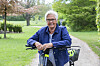 Ada står med cykel på sti i grøn park en lys dag