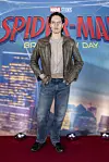 Person står på rød løber foran Spider-Man premierebagvæg.