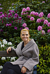 Inger Støjberg på bænk i park foran lyserøde og hvide rhododendron