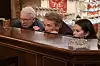 Tre personer kigger spændt op over en bar i en elegant barindretning.