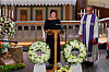 Aina Tufte taler ved talerstol omgivet af blomsterkranse i Horten Kirke.