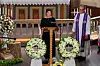 Aina Tufte taler ved talerstol omgivet af blomsterkranse i Horten Kirke.