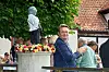 Folk ved Rosenfestivalen i Bogense 2026 står ved en statue pyntet med roser