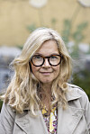 Portræt af Sisse Sejr udendørs med beige frakke og briller.