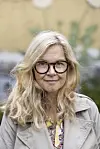 Portræt af Sisse Sejr udendørs med beige frakke og briller.