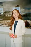 Samira Nawa i hvid habit holder en rød 'PYT'-knap foran stort bjergfotografi på kontor