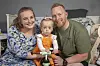 Cecilie og René sidder tæt med datteren Freja på en lille løbecykel i børneværelset