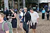 Folk går på skovsti foran boder og Smukfest-skilt i træbevokset område.