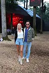Par står på skovbund foran teltscene med rødt lys under udendørs event.