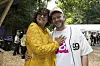 To smilende festivalgæster står arm i arm i skovområde på musikfestival.
