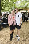 To unge festivalgæster står og smiler i madområdet på Smukfest omgivet af andre besøgende.