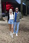 To festivalgæster står på skovstien foran en oplyst scene på Smukfest.