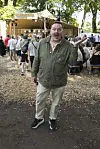 Smilende festivalgæst står i skovområde foran udendørsscene på Smukfest.