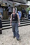 Person står på træflis foran bar på Smukfest 2026 omgivet af andre festivalgæster.