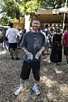 Mand med to dåsedrikke står foran udendørsscene på Smukfest omgivet af publikum.
