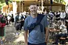 Mand står foran udendørsscene omgivet af festivalgæster på Smukfest i skoven.