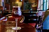 Glas med mørkt øl på blankt træbord i hyggelig pub
