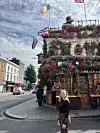 Person foran blomsterpyntet pub med britiske og irske flag på hjørne i by