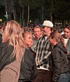 Unge mennesker står tæt sammen blandt en stor publikumsmængde ved en udendørs koncert.
