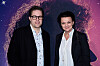 To personer poserer foran en lilla og blå filmplakat ved en filmpremiere.