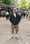 Person poserer på skovsti foran boder og festivalgæster på Smukfest dag 3 2026.
