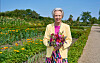 HKH Dronning Ingrid Gråsted med blomsterbuket i farverig have på solrig dag