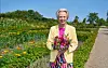 HKH Dronning Ingrid Gråsted med blomsterbuket i farverig have på solrig dag