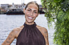 Person fra Temptation Island smiler ved vandet med grønne planter i forgrunden.