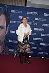 Kvinde står på rød løber foran blå fotovæg med teksten Dobbeltspil.