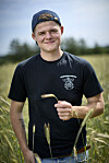 Jonathan Nielsen står i en kornmark med Elevsgården T-shirt og kasket vendt baglæns.