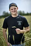 Jonathan Nielsen står i en kornmark med Elevsgården T-shirt og kasket vendt baglæns.
